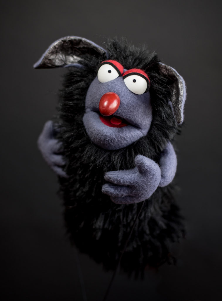 Black rat puppet with overly large ears, red nose, and beady eyes