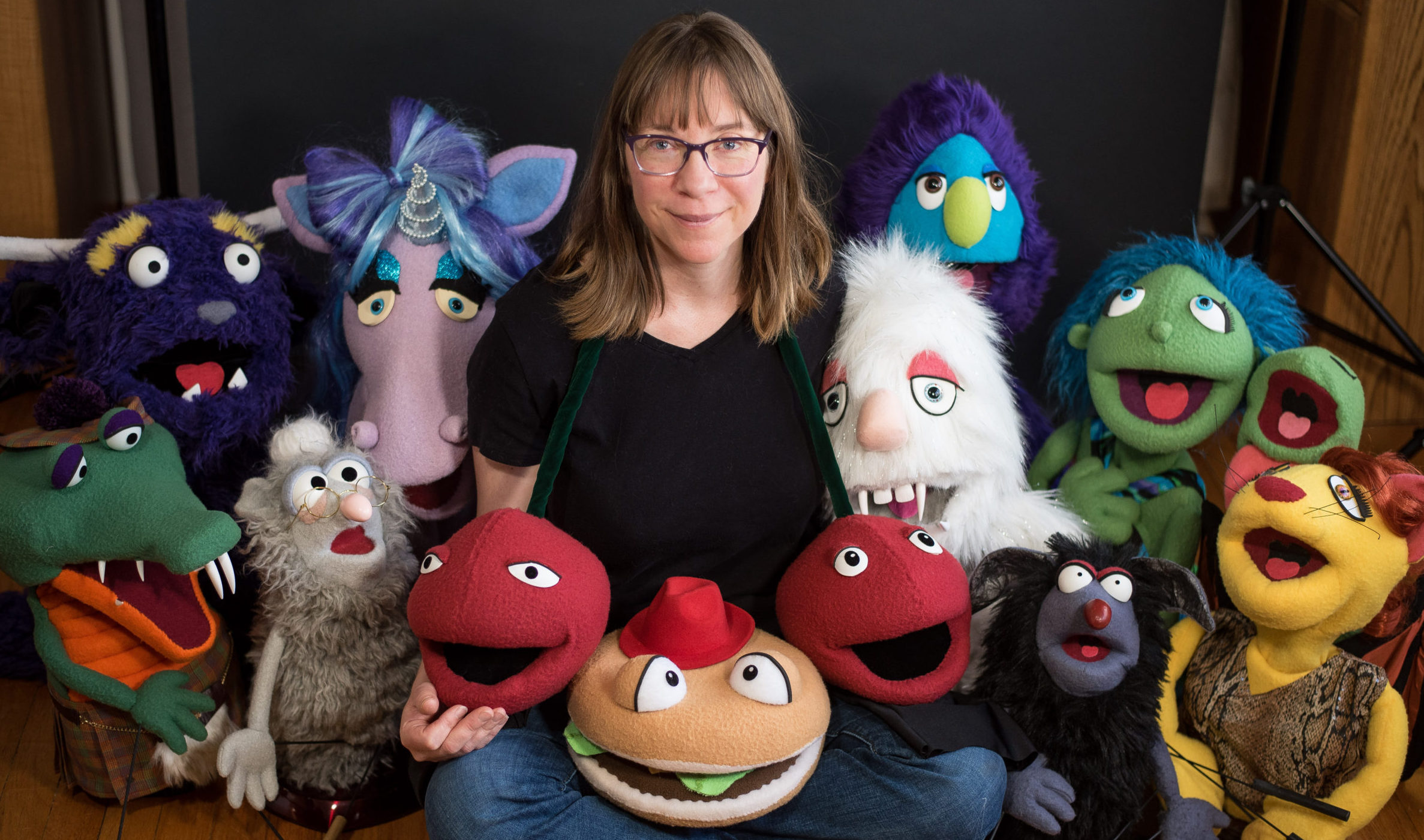 Laurie surrounded by a group of puppets